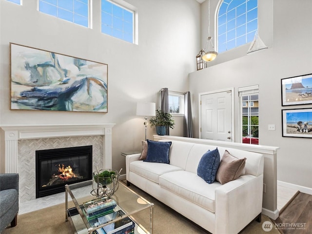 living area featuring a tiled fireplace, plenty of natural light, wood finished floors, and baseboards