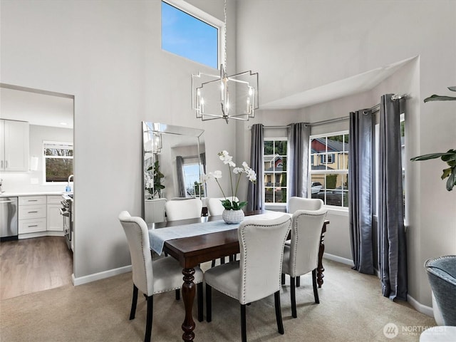 dining area with an inviting chandelier, a high ceiling, light colored carpet, and a healthy amount of sunlight