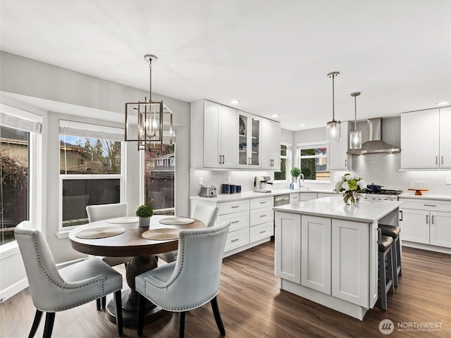 kitchen featuring dark wood finished floors, a notable chandelier, wall chimney exhaust hood, and a sink