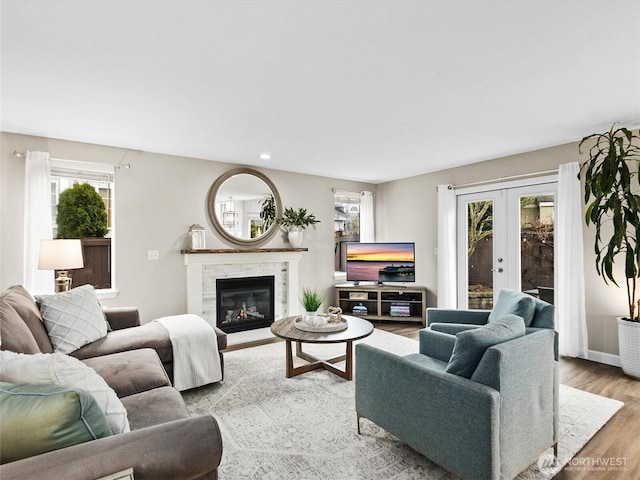 living room with baseboards, recessed lighting, french doors, wood finished floors, and a glass covered fireplace