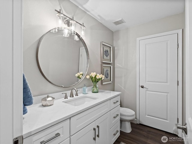 bathroom featuring visible vents, toilet, wood finished floors, and vanity