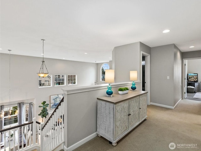 hallway featuring recessed lighting, baseboards, light carpet, and an upstairs landing