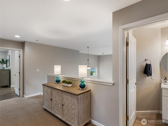 hall with recessed lighting, light colored carpet, and baseboards