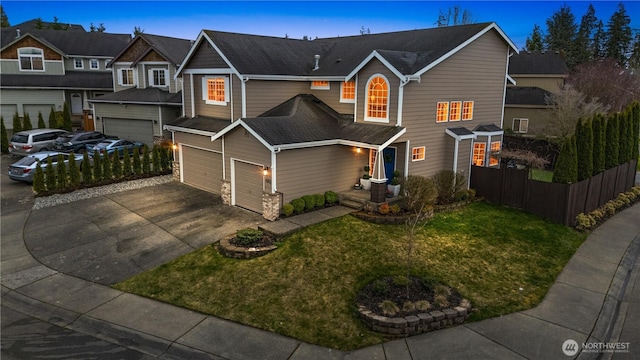 traditional home with a front lawn, an attached garage, fence, and driveway