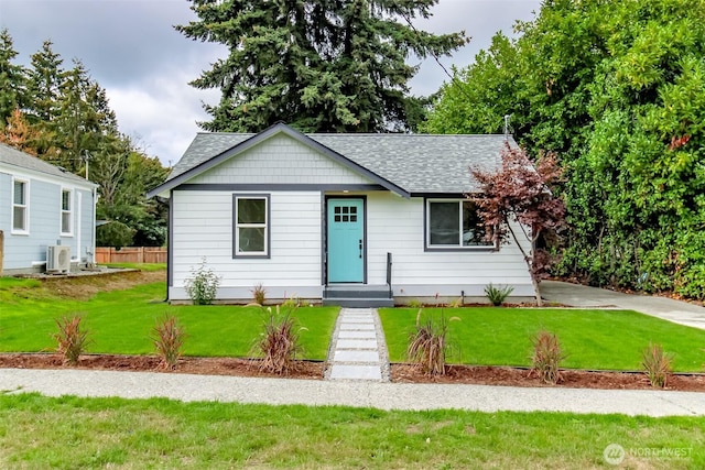 view of front of home featuring a front yard, ac unit, fence, and roof with shingles