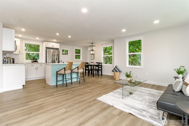 living room featuring recessed lighting, baseboards, and light wood-style floors