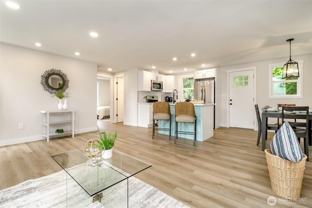 living room with recessed lighting, light wood-type flooring, and baseboards