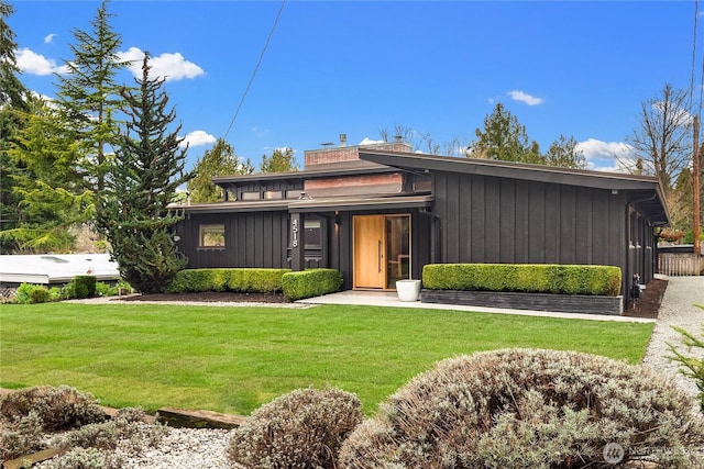 mid-century inspired home with a front lawn, board and batten siding, and a chimney