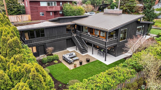 back of house featuring stairs, a lawn, metal roof, a patio area, and a standing seam roof