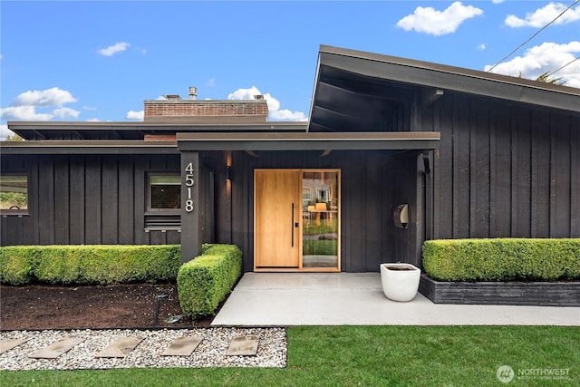 view of exterior entry featuring a lawn and board and batten siding