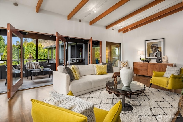 living area with lofted ceiling with beams and wood finished floors