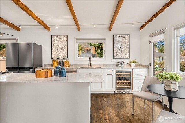 bar featuring beverage cooler, dark wood finished floors, beam ceiling, freestanding refrigerator, and a sink