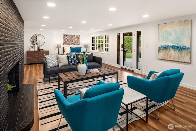 living room with recessed lighting, baseboards, a large fireplace, and wood finished floors