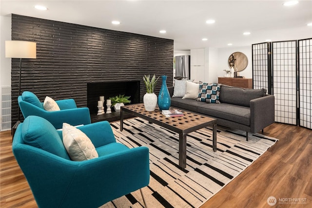 living room featuring recessed lighting, wood finished floors, and a large fireplace