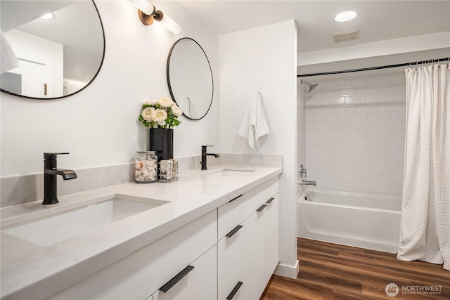 bathroom with shower / bath combination with curtain, wood finished floors, visible vents, and a sink