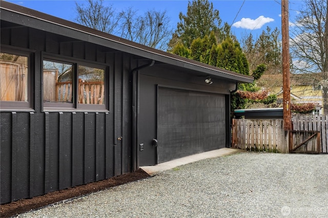 garage with gravel driveway and fence