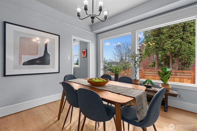 dining room with light wood-style flooring, baseboards, and a chandelier