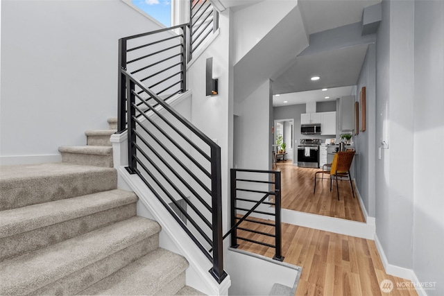 stairway featuring recessed lighting, wood finished floors, and baseboards