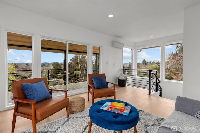 living room featuring a wealth of natural light, recessed lighting, a wall mounted air conditioner, and light wood-style floors