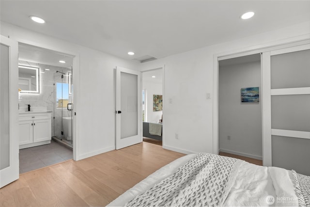 bedroom featuring recessed lighting, baseboards, light wood-style flooring, and ensuite bathroom