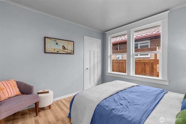 bedroom featuring ornamental molding, baseboards, and wood finished floors