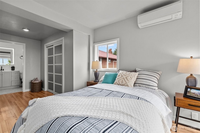 bedroom with wood finished floors, baseboards, and a wall mounted AC