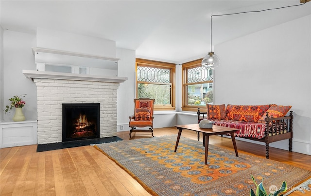 living room featuring a brick fireplace and wood finished floors