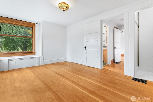 spare room with light wood-style flooring, baseboards, and visible vents