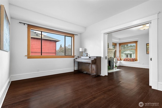 spare room featuring baseboards, dark wood-style flooring, and a fireplace