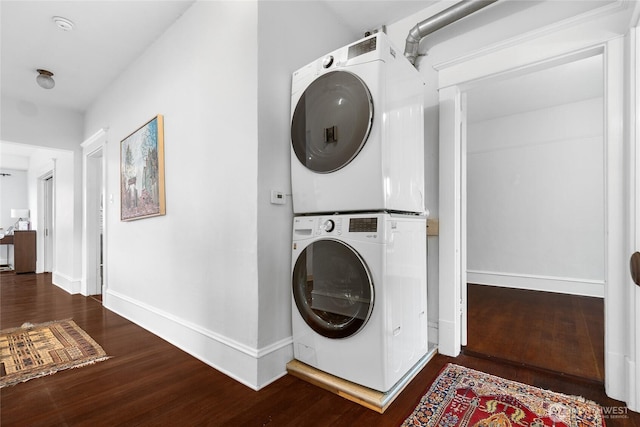 laundry room featuring laundry area, wood finished floors, baseboards, and stacked washing maching and dryer