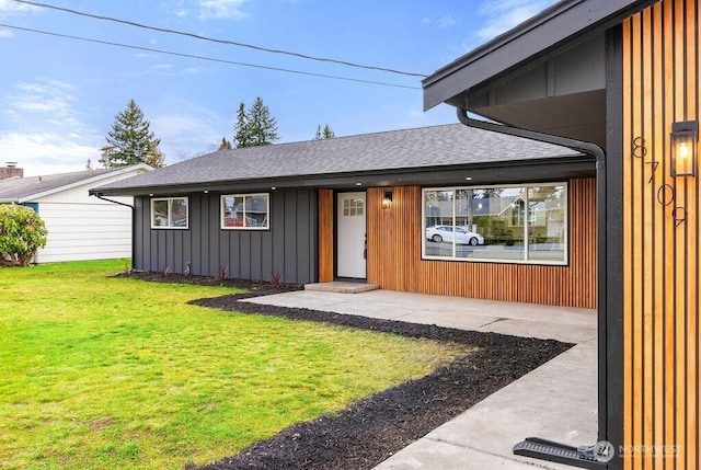 exterior space with board and batten siding, a shingled roof, and a front lawn