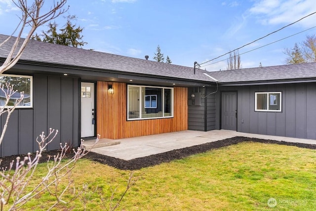 exterior space featuring a patio, a lawn, board and batten siding, and roof with shingles