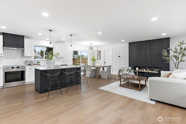 living room featuring recessed lighting, light wood-type flooring, baseboards, and a chandelier