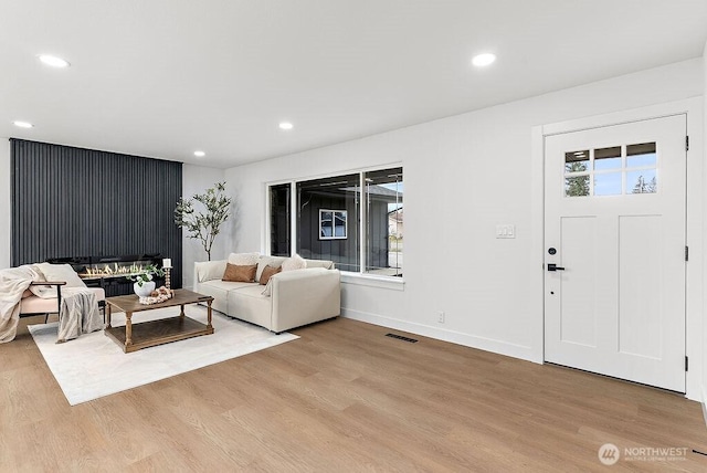 living area with recessed lighting, light wood-type flooring, baseboards, and visible vents