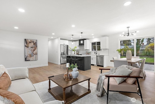 living room with recessed lighting, baseboards, light wood-style floors, and an inviting chandelier