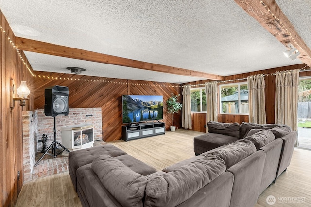 living room with wooden walls, beamed ceiling, a textured ceiling, and a healthy amount of sunlight