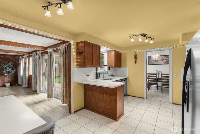 kitchen with a sink, a peninsula, a wealth of natural light, and light countertops