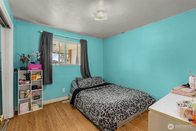 bedroom featuring wood finished floors, baseboards, and a textured ceiling