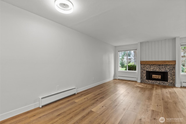 unfurnished living room featuring a baseboard heating unit, baseboards, light wood-type flooring, and a fireplace