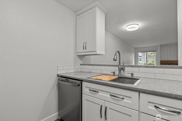 kitchen with white cabinets, dishwasher, baseboards, and a sink