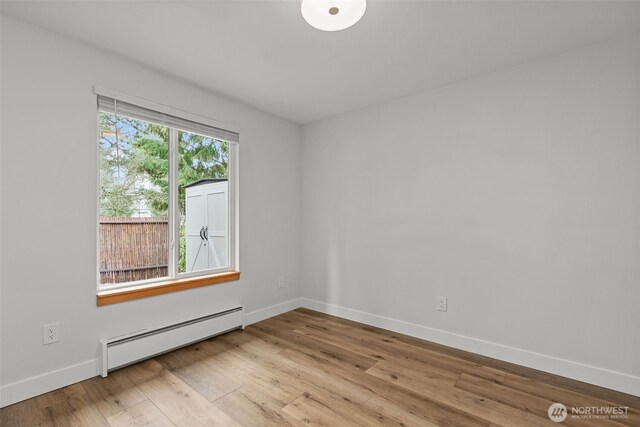 spare room featuring baseboard heating, baseboards, and wood finished floors