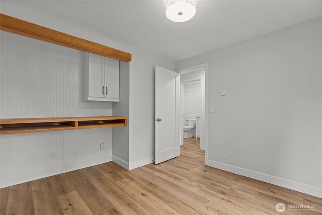 interior space featuring baseboards, built in desk, and light wood finished floors