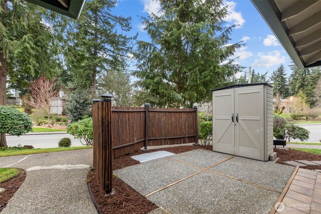 view of patio / terrace with an outbuilding, a storage unit, and fence