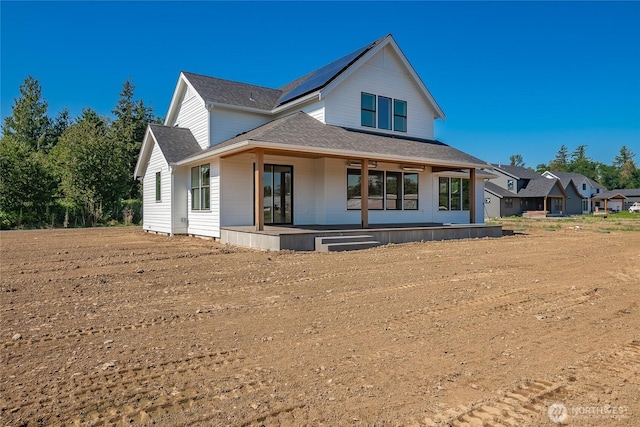 view of front of property featuring solar panels, a porch, and roof with shingles