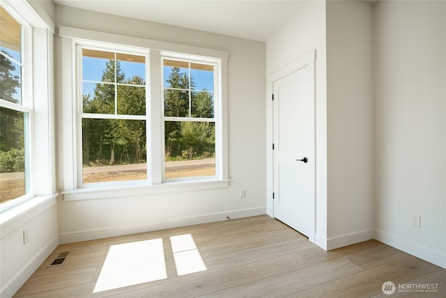 unfurnished room featuring light wood-style flooring, baseboards, and visible vents