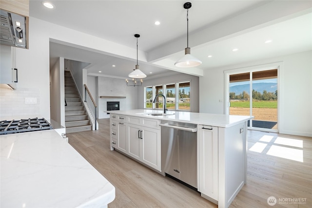 kitchen with tasteful backsplash, appliances with stainless steel finishes, light wood-style floors, white cabinetry, and a sink