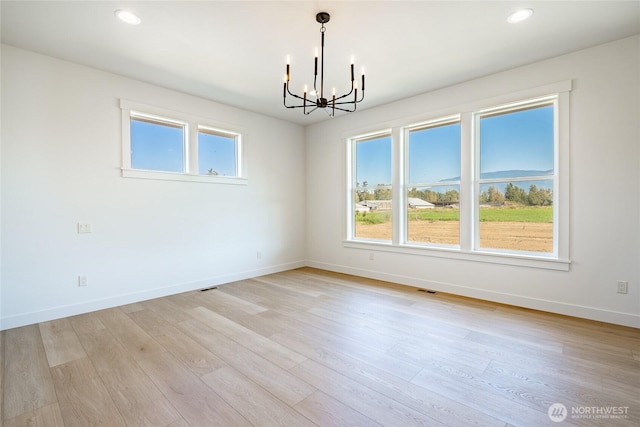 spare room featuring recessed lighting, light wood-type flooring, baseboards, and a chandelier