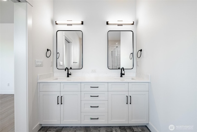 bathroom with a sink, baseboards, wood finished floors, and double vanity