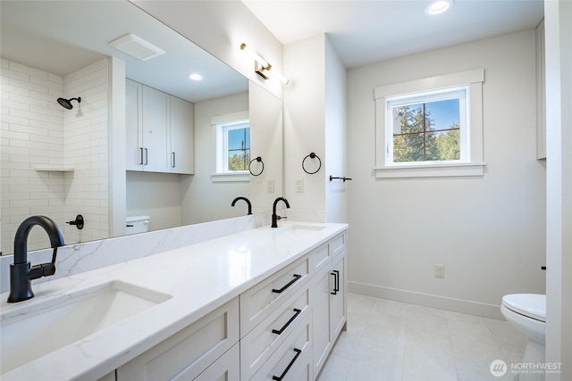 bathroom with a sink, tiled shower, baseboards, and toilet