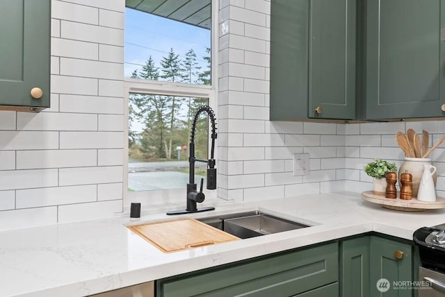 kitchen featuring electric stove, light stone counters, a sink, backsplash, and green cabinetry